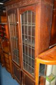 A 20TH CENTURY LEAD GLAZED TWO DOOR BOOKCASE above double cupboard doors, approximate width 99cm x
