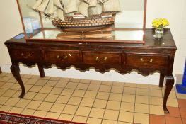 A GEORGIAN OAK DRESSER BASE with four short drawers and brass handles, wavy apron on front
