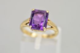 A 9CT GOLD AMETHYST RING, the rectangular amethyst within a four claw setting to the openwork