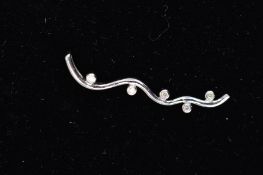A 9CT WHITE GOLD DIAMOND PENDANT, designed as a wavy line, collet set to either side with five