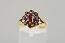 A 9CT GOLD GARNET CLUSTER RING, the oval garnet within a tiered circular garnet surround to the open