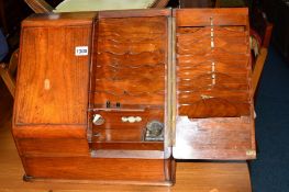 A VICTORIAN WALNUT SLOPED TWO DOOR STATIONARY CABINET, the interior revealing two inkwells and a