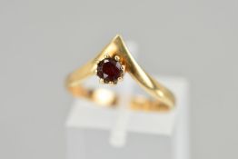A 9CT GOLD GARNET RING, the circular garnet within an eight claw setting to the wishbone shaped