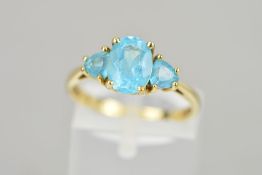 A 9CT GOLD TOPAZ RING, designed as a central oval shape topaz flanked by triangular topaz, import