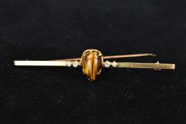 TIGERS EYE AND DIAMOND BAR BROOCH, pear shape cabochon tiger-eye flanked by two old mine cut