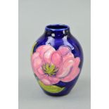 A SMALL MOORCROFT POTTERY VASE, 'Magnolia' pattern on blue ground, impressed and painted marks to