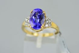 A MODERN TANZANITE AND DIAMOND RING centring on an oval mixed cut tanzanite measuring 11.5mm x 7.
