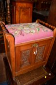 AN EDWARDIAN WALNUT PIANO STOOL with needle work top and carved fall front compartment containing