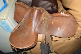 A BROWN LEATHER HORSE SADDLE AND STRIRRUPS and an ercol strick back chair (2)