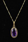 A 9CT GOLD AMETHYST PENDANT AND CHAIN, the oval amethyst within a collet setting with rope twist
