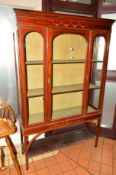 AN EDWARDIAN MAHOGANY AND INLAID GLAZED DISPLAY CABINET on square tapering supports united by an