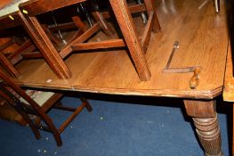 AN EDWARDIAN OAK WIND OUT DINING TABLE on fluted legs with a single additional leaf, approximate