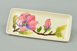 A MOORCROFT POTTERY RECTANGULAR PIN TRAY, 'Magnolia' pattern on cream ground, impressed marks to