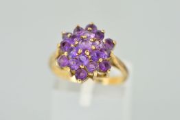 A 9CT GOLD AMETHYST CLUSTER RING designed as a tiered cluster of claw set circular amethyst,