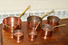 A SET OF SIX EARLY 20TH CENTURY COPPER PANS, with brass hooped handles