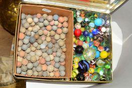 A COLLECTION OF MARBLES, mixture of stone and glass examples, contained in a lithographed tin