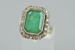 AN EMERALD AND DIAMOND DRESS RING, designed as an emerald cut emerald within a single cut diamond