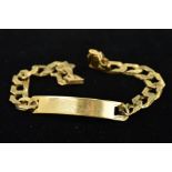 A 9CT GOLD IDENTITY BRACELET, the plain curved panel with personal engraving to the textured curb