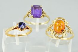 THREE DRESS RINGS comprising of an amber single stone with scroll decoration, a rectangular single