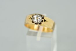 A DIAMOND RING designed with a collet set brilliant cut diamond to a claw surround and wide band,