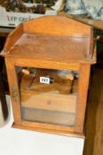 AN OAK PIPE SMOKERS CABINET with a central drawer and glazed hinged door, approximate height 37cm (