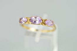 A 9CT GOLD AMETHYST RING designed as three claw set graduated oval amethysts interspaced by curved