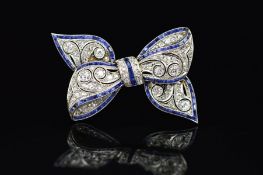 AN EARLY TO MID 20TH CENTURY GOLD SAPPHIRE AND DIAMOND RIBBON BOW BROOCH, measuring approximately
