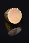 A GOLD SEAL RING, the oval chalcedony carved to depict a lion's head atop a castle of the textured