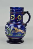 A 16TH CENTURY STYLE BLUE GLASS EWER, the cylindrical neck applied with a band and handle and