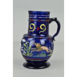A 16TH CENTURY STYLE BLUE GLASS EWER, the cylindrical neck applied with a band and handle and