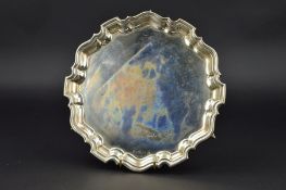 AN ELIZABETH II SILVER SALVER, of circular form, pie crust edge, on three scrolled feet, maker