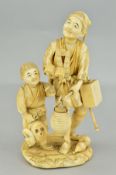 A LATE 19TH CENTURY JAPANESE SECTIONAL IVORY OKIMONO OF A MAN AND A BOY, the boy holding masks,