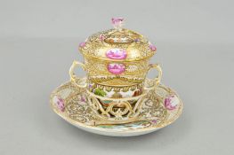 A 19TH CENTURY BERLIN PORCELAIN TWIN HANDLED CHOCOLATE CUP AND COVER ON A SAUCER, the domed cover