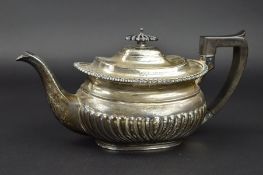 AN EDWARDIAN SILVER TEAPOT OF GEORGIAN STYLE, gadrooned rim, half reeded, ebonised fitments,