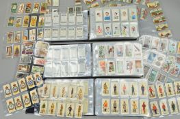 A CIGARETTE CARD COLLECTION, in three ring binder albums featuring various manufacturers including