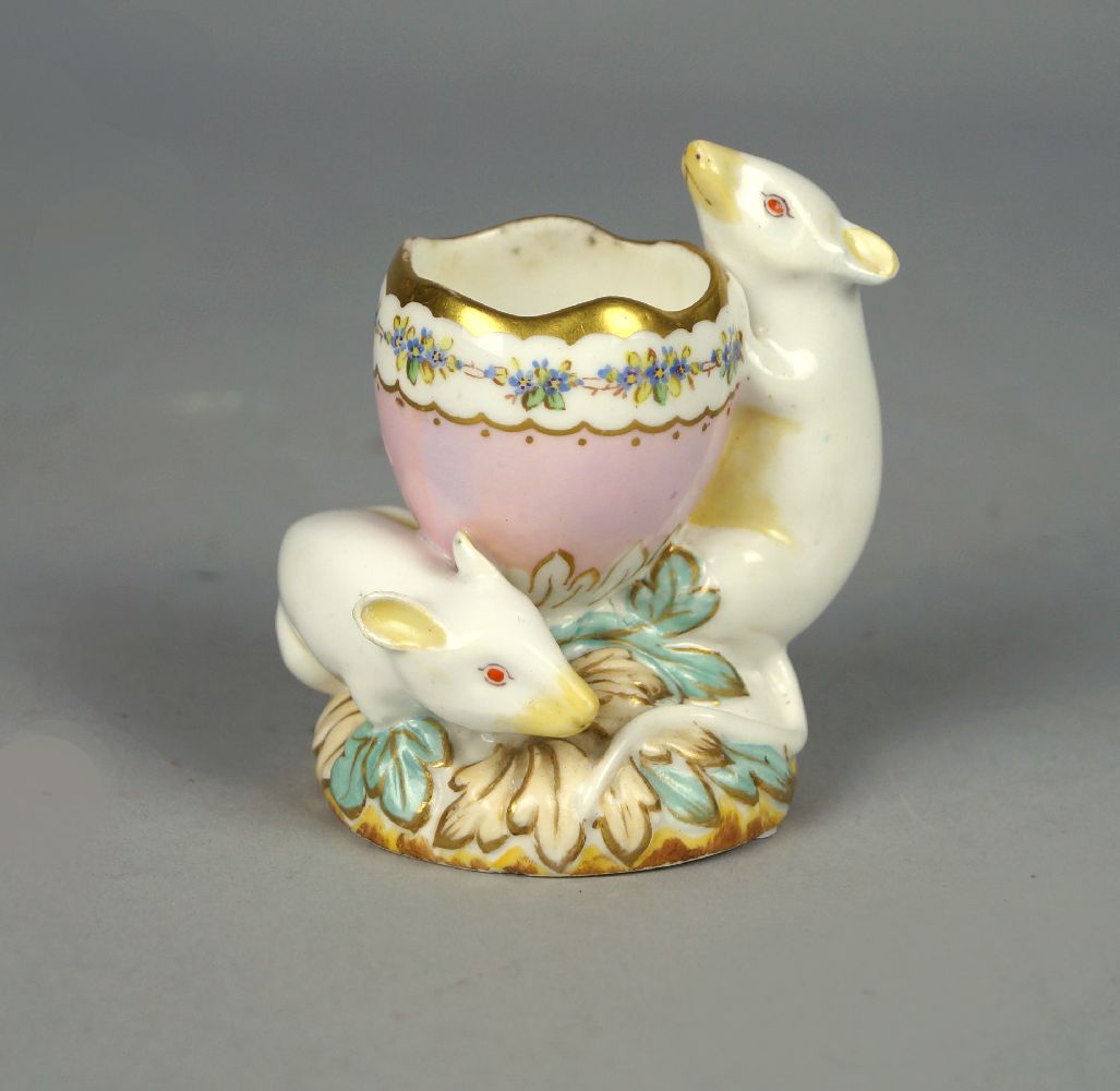 A Volkstadt porcelain egg cup, late 19th century, modelled as two mice supporting a cracked egg,