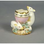 A Volkstadt porcelain egg cup, late 19th century, modelled as two mice supporting a cracked egg,