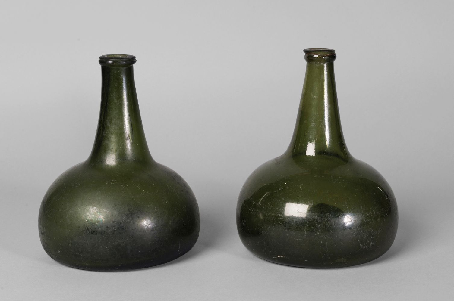 Two Georgian green glass onion form bottles, 18.5cm high (2)