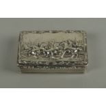 A George IV silver snuff box, maker TS, the hinged cover moulded with a battle scene, with scroll