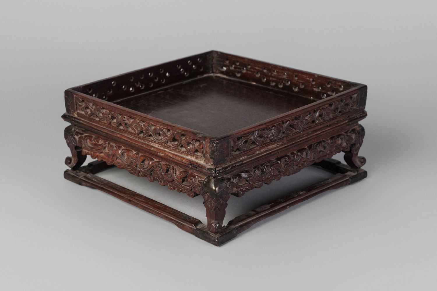 A Chinese hardwood square stand, late 19th century, with carved and pierced gallery and carved