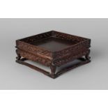 A Chinese hardwood square stand, late 19th century, with carved and pierced gallery and carved