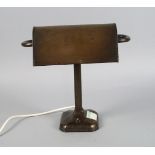 A patinated metal desk lamp, 20th century, with a moveable reflector on a square section column, the