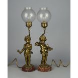 A pair of polished brass models of cherubs, each representing the arts of sculpture and painting,