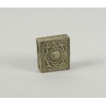 A Tibetan silver square gow, 19th century, with hinged lid, embossed with central dome and foliate