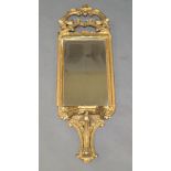 A giltwood wall mirror, 19th Century, the pierced crest with scrolling foliate decoration, above