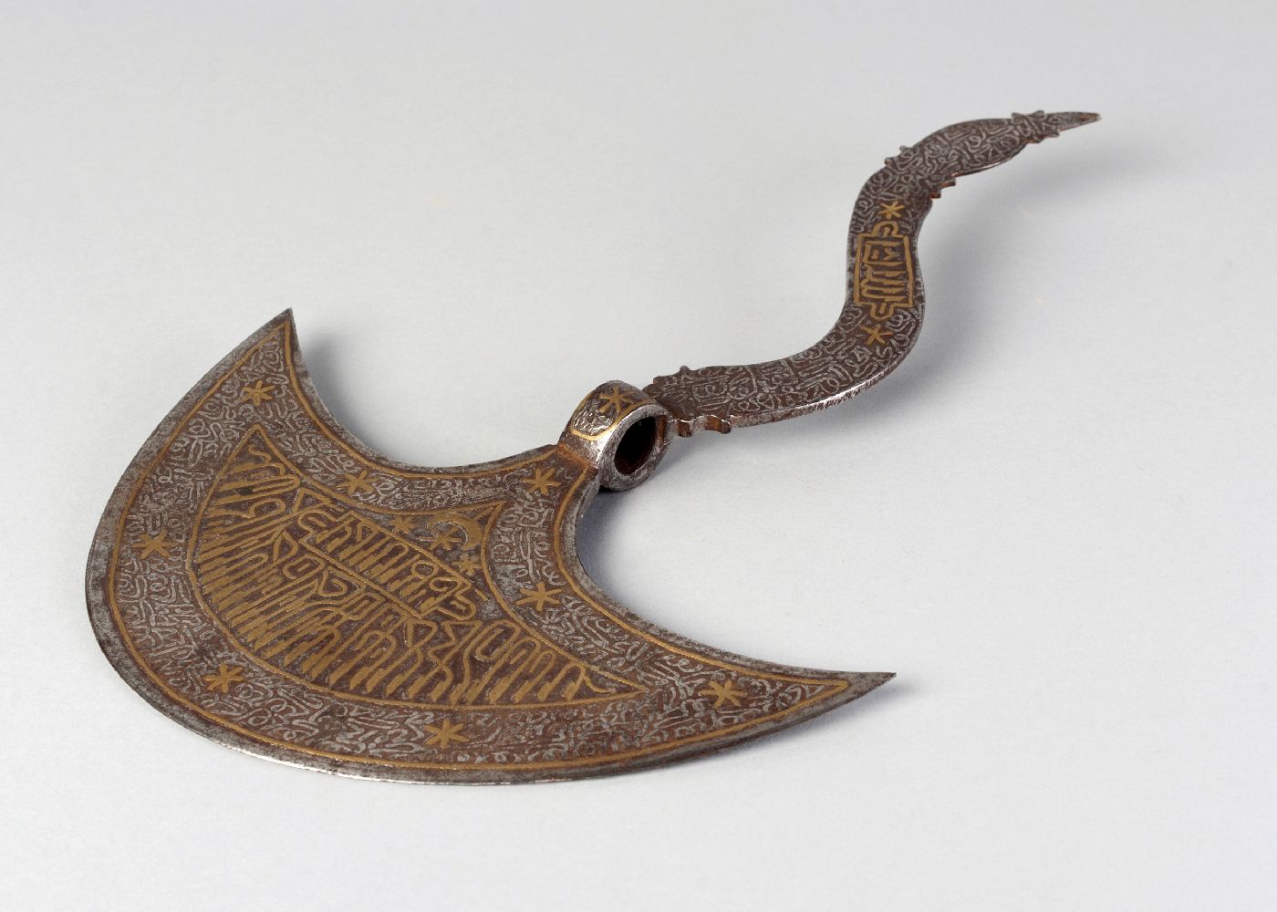 A damascened steel ceremonial axe head, tabar, 19th century, inlaid with bands of calligraphy