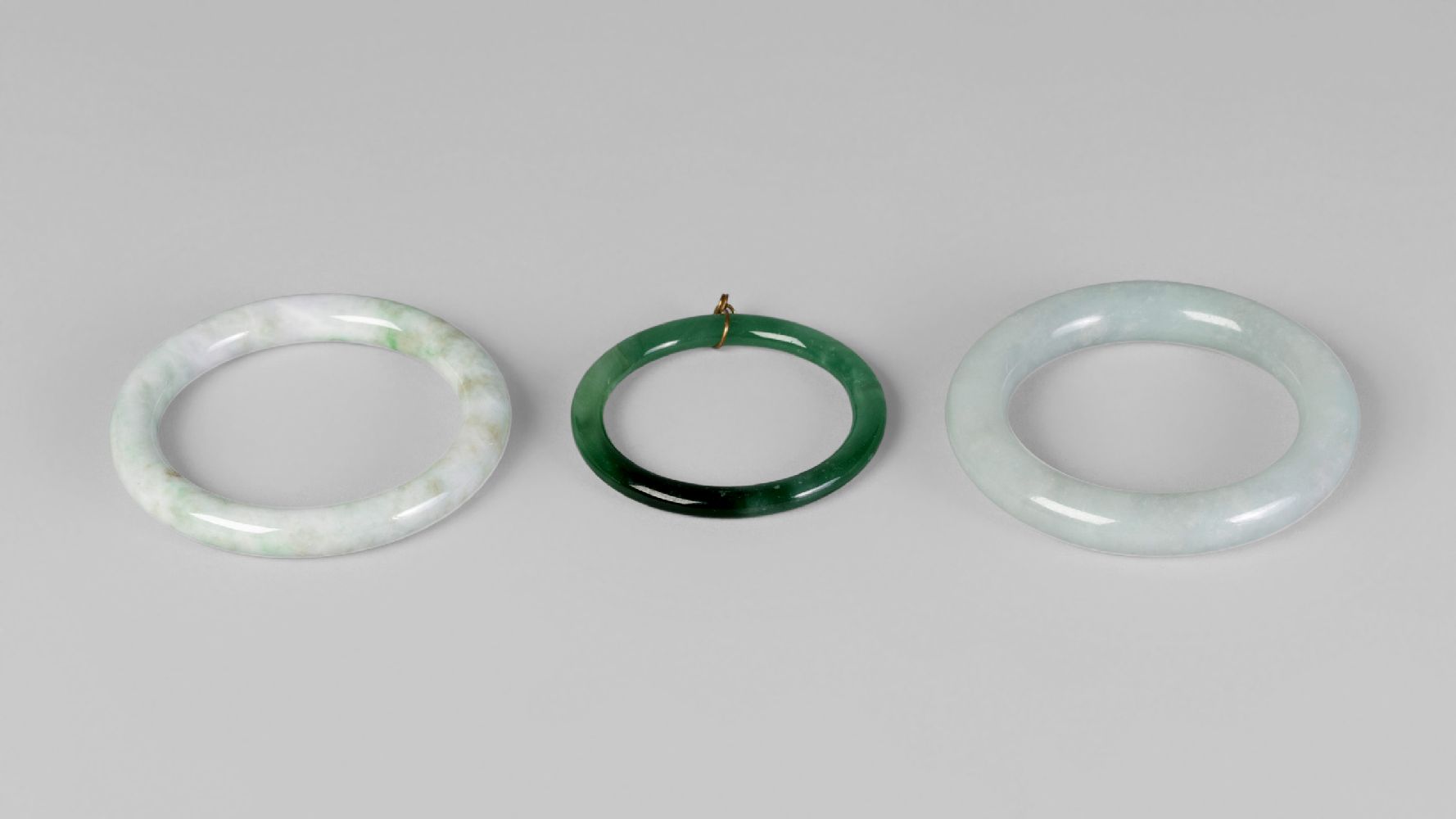 Two Chinese pale green hardstone bangles, 20th century, 8cm diameter, and a child's bangle (3)