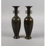 A pair of Chinese patinated bronze long vases, late 19th century, with angular fretwork handles,