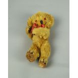 A miniature plush bear, 20th century, with a smiling face and plastic eyes, 22cm high