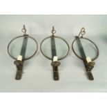 A set of three steel wall lights, 20th century, the back plates with hooks and light sconces, hung